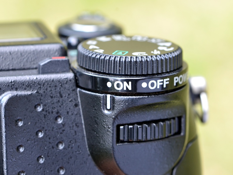 <b>左手側の横（上部）には、露出補正ボタンとストロボモードボタンが並ぶ。それらの機能の設定・調節は、各ボタン＋背面のダイヤルで行なう。ちなみに両ボタンを同時に押すと、ストロボ補正になる</b>