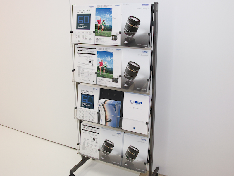 <b>会場ではカタログの他、60周年の歩みを記した小冊子（右）やタムロンのカンパニーガイドがもらえる</b>