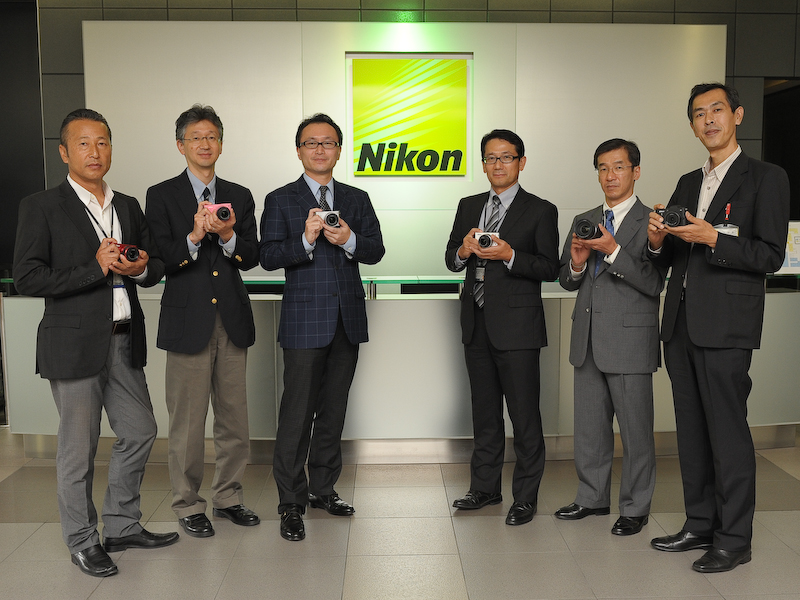 <b>今回話を伺ったメンバー。左から野島章氏（全体のデザインディレクションを担当）、内山重之氏（AFを担当）、野崎弘剛氏（商品企画を担当）、鈴木政央氏（開発全体のとりまとめを担当）、守山啓二氏（レンズ関係全般を担当）、井村好男氏（ボディの設計および開発を担当）。</b>