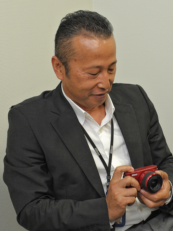 <b>全体のデザインディレクションを担当した野島章氏。「ボディとレンズという全体で見ると非常に完成度の高いサイズに仕上がっています。是非使ってバランスの良さを実感してください」</b>