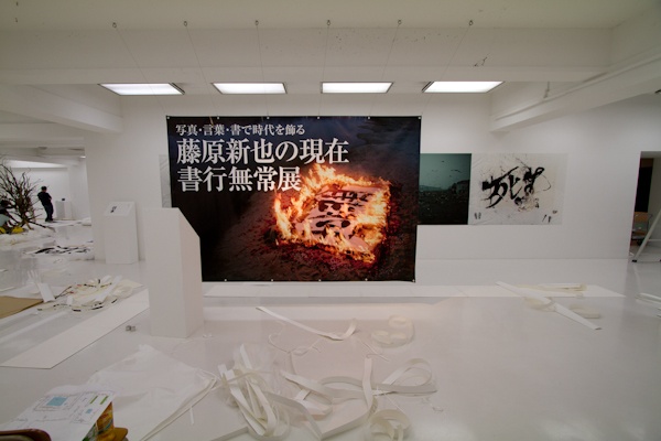 <b>写真展の設営や準備は大勢のスタッフによって、オープン前日の深夜遅くまで続いていた。下段左側は今回の書行無常ロケの撮影現場で、藤原さんが書を書くときに纏う大切な衣装を作ったファッションデザイナーの青木貴志さん。スタイリストでもある青木さんのセンスが光る洋服は100年くらい前の端切れなどから作られているそうだ。すっごく素敵な衣装でボクも着たいなー!</b>