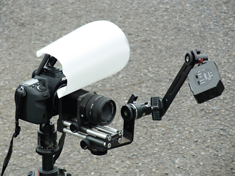 <b>ノボフレックスからかつて発売されていたオートベローズは、ユニークなカラクリで“完全自動絞り”を実現したアイデア商品だった。今回はこのベローズの機能をデジタルカメラで活かすためペンタックス「K-5」に装着。内蔵ストロボ用ディフューザーに加え、スレーブストロボ「ヒカル小町」も装備した。レンズは専用の「ノフレクサー60mmマクロ」を装着。三脚に据えてはいるが、手持ち撮影用の高倍率マクロシステムとして組んでみた</b>