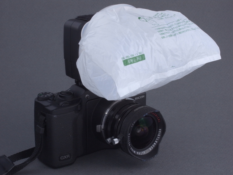 <b>タッパーの中心に錐で穴を開け、息を吹き込むとコンビニ袋が風船のように膨らむ仕組みになっている（笑）。これにより散光効果が高まり、レンズによるケラレをより効果的に防ぐことが出来るのだ</b>