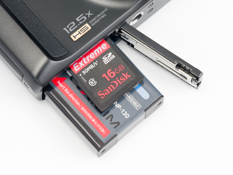 <b>記録メディアはSDXC/SDHC/SDメモリーカード（ほんとは裏向きに挿入する）。電源はCIPA基準で約480コマ撮れるリチウムイオン電池</b>