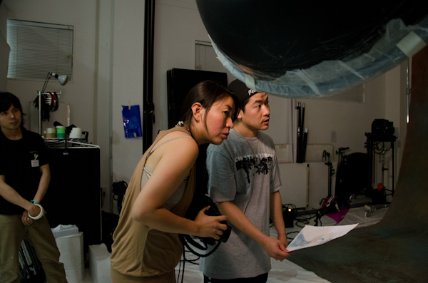 <b>この日は、いま大人気急上昇中の異色のビジュアル系ロックバンド「女王蜂」のCDジャケット他の撮影。身体に特殊メイクを施し、ムラ布バックドロップ&amp;ストロボヘッドにカラーフィルターを使用しての怪しいゴージャス満点のスタジオ撮影だった</b>