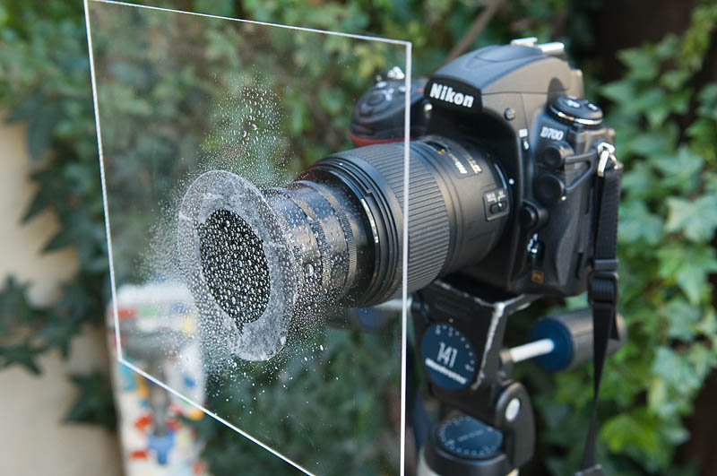 <b>ケンコー製のマルチホルダー用アダプターリングに両面テープで透明アクリル板を取り付けた。レンズと板の間の距離を調整するために延長筒が入れてある。延長筒は「エクステンションチューブ」、「エクステンションアダプター」、「保護リング」などの名称で販売されている</b>