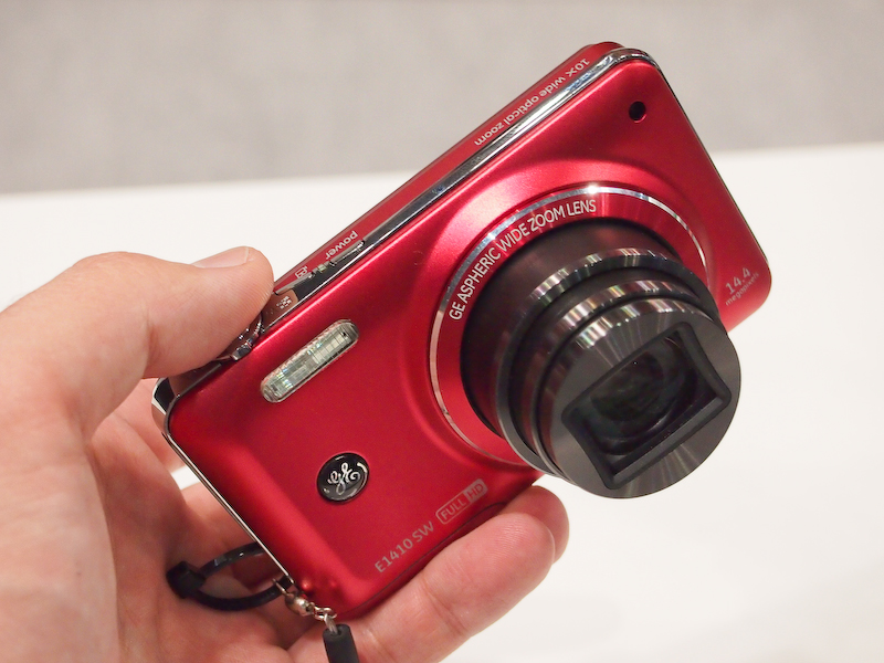 <b>E1410SW。厚さ19mmの光学10倍ズーム搭載機。3月に1万5,000円前後で発売する。1,440万画素CMOSセンサー、3型液晶モニターなどを備える。リチウムイオン充電池仕様</b>