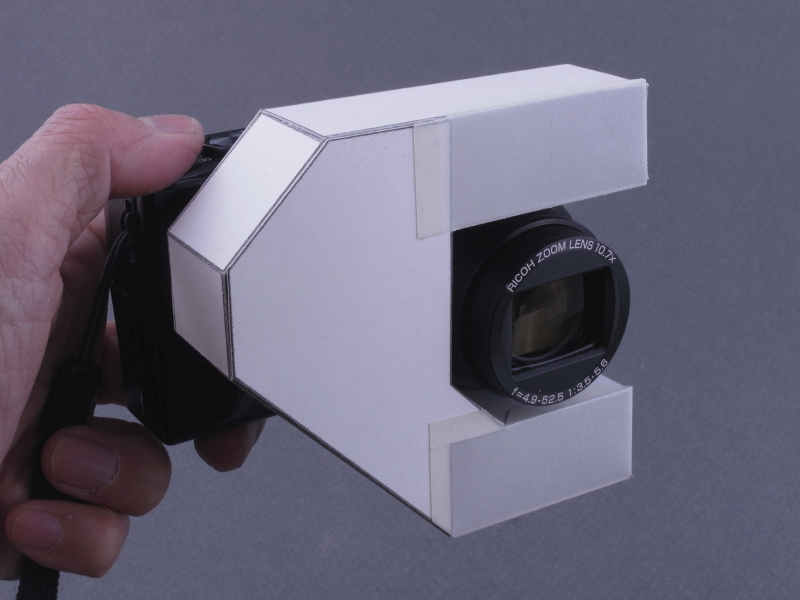 <b>自作の「レフレックスタイプ・ディフューザー」を装着した、リコーCX6。内蔵ストロボの光をディフューザー内部で反射させ、レンズ上下の開口部に導いている。これにより、リコー独自の「1cmマクロ」を活かしたストロボ撮影が可能になる</b>