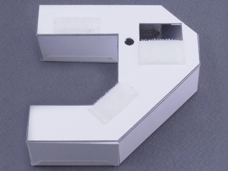 <b>裏側には、CX6の内臓ストロボの位置に合わせ、四角い穴を開けている（その脇の小さな穴はAF補助光用）。さらにカメラに取り付けるためのマジックテープを、3カ所に貼り付ける</b>