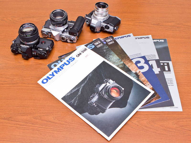 <b>OMシリーズのカタログ。上のカメラは左からOM-4、M-1（OM-1の前身）、OM-D E-M5</b>