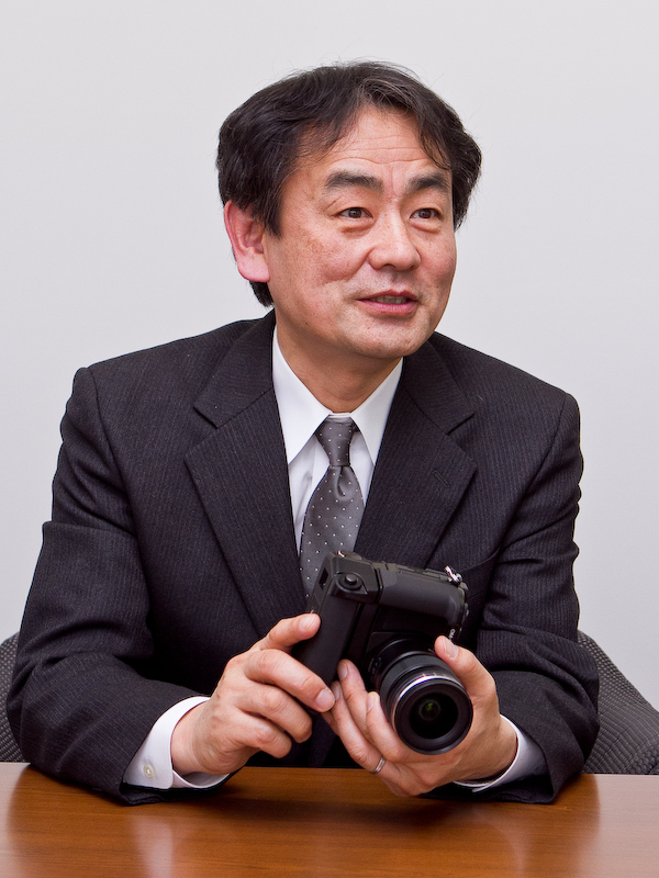 <b>芳賀満裕氏（開発全般のリーダー）。「このカメラでは是非作品を撮って頂きたい。オリンパスでは単焦点の明るいレンズも出していますし、<a href="http://dc.watch.impress.co.jp/docs/news/20120208_510362.html"><b>60mmのマクロや75mmの大口径レンズ</b></a>といったも今後出していきますので、ぜひ楽しんで欲しいと思います」</b>