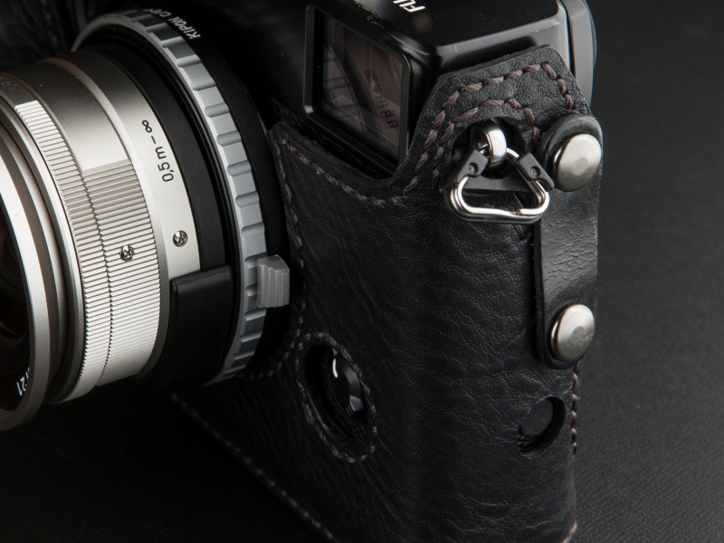 <b>向かって右側の側面は、吊り環にケースをフックし、ボタンで固定するスタイルだ</b>