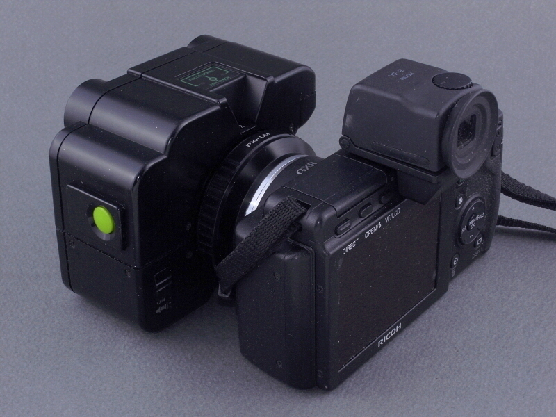 <b>左斜め後方から見たところ。マウント変換リングのくびれが、いかにも“連結”という感じだ。レンズ左横の赤いボタンがAF作動スイッチ。レンズ後部左下には、アラームON/OFFスイッチがある。</b>