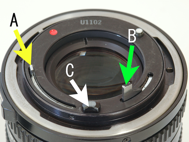 <b>機械的な情報伝達：キヤノンのニューFDレンズの後部。Aは絞り情報の伝達レバー、Bは自動絞りの絞り込み情報の伝達レバー、Cはレンズの開放Fナンバーの伝達ピン。このように伝達する情報ごとにピンやレバーが必要であった。</b>