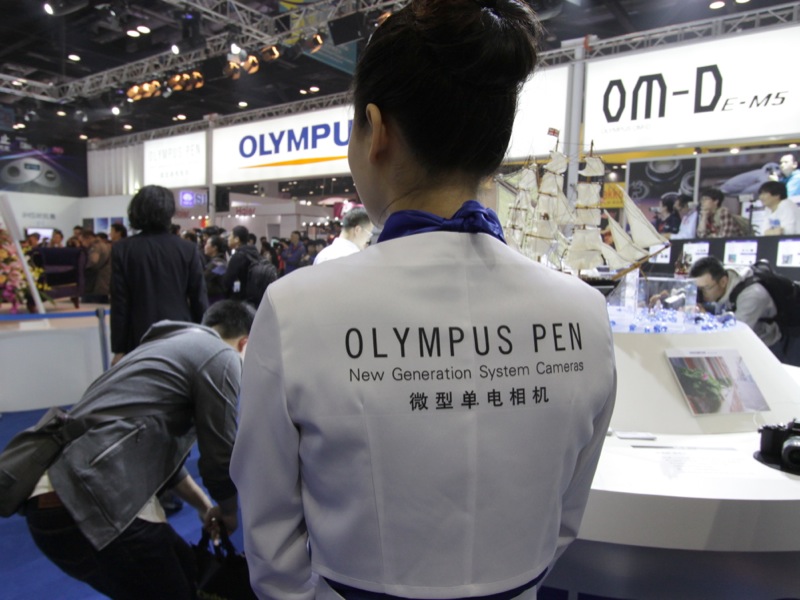 <b>コンパニオンのユニフォームの背中にOLYMPUS PENのプリント。</b>
