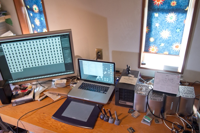 <b>渋谷に近い自宅兼事務所の1Fは所氏の制作のスペースだ。Mac環境をメインにエプソンのA2プリンター、PX-5002やその他のデジタル機器で埋め尽くされ、電源が入りっぱなしなので、熱がこもらないように窓のカーテンはいつも閉まっている</b>
