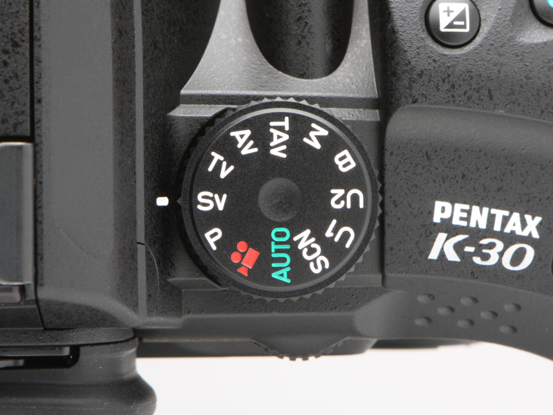 <b>モードダイヤルはシャッターボタン側のトップカバーに備わる。SV（感度優先自動露出）はISO感度を任意の値に設定するモード、TAV（シャッター＆絞り優先自動露出）は任意で設定したシャッター速度と絞り値で適正露出になるようISO感度を自動的に設定するモードだ。</b>