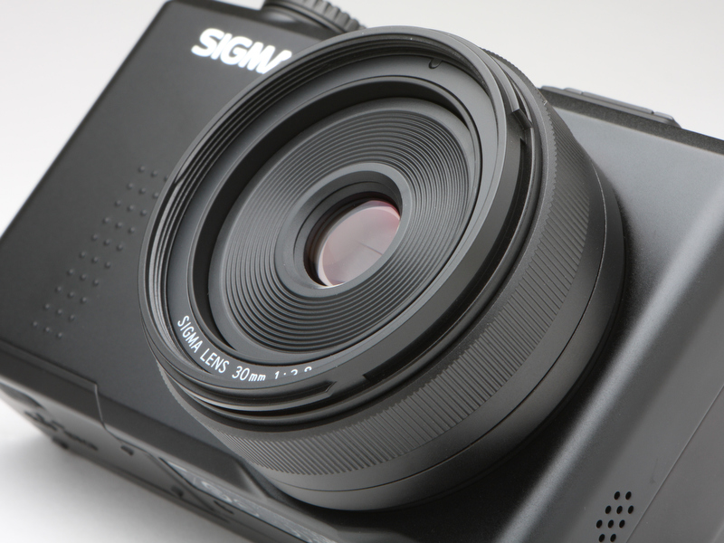 <b>搭載するSIGMA LENS 30mm F2.8。最短撮影距離は28cm。フォーカスリングを備え、AF合焦後MF操作によるピントの微調整も可能としている。フィルター径は49mm</b>