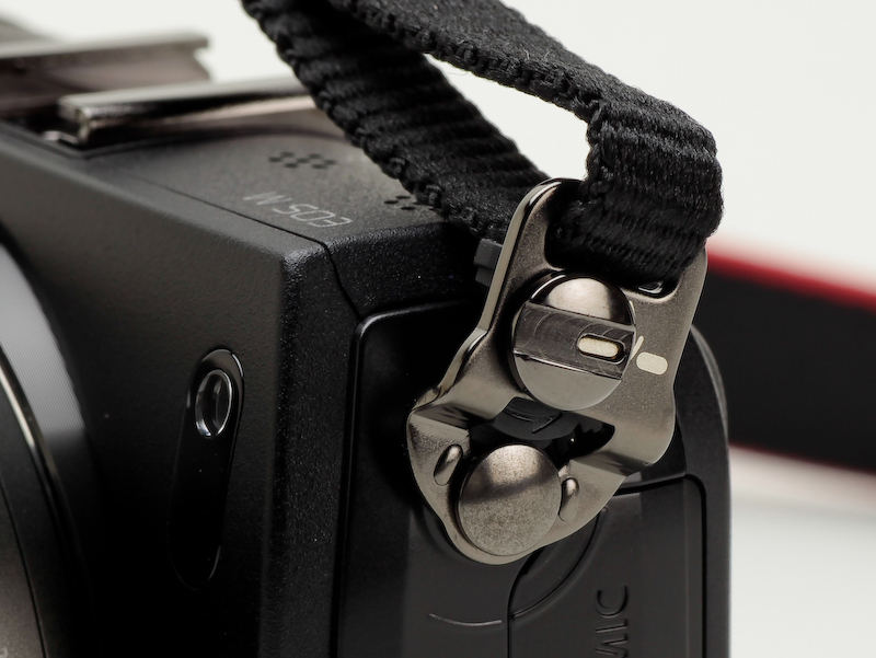 <b>ストラップが360度回転するので取り回しは良さそうだ。ロックと解除はコインでつまみを回して行なう。レンズにストラップ穴の無いEFレンズであれば、どのレンズを装着した場合でも耐えられるという</b>