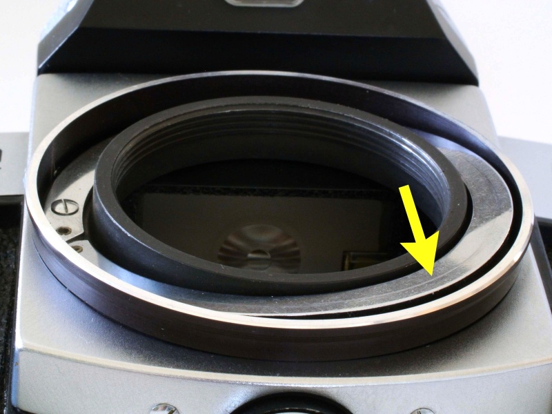 <b>ペンタコンスーパーのボディ側にはマウント周囲にリング状の板ばねが設けられており、その平面部（矢印）にレンズ側の連動ピンが当たって押すことにより設定絞り情報を伝えている。</b>