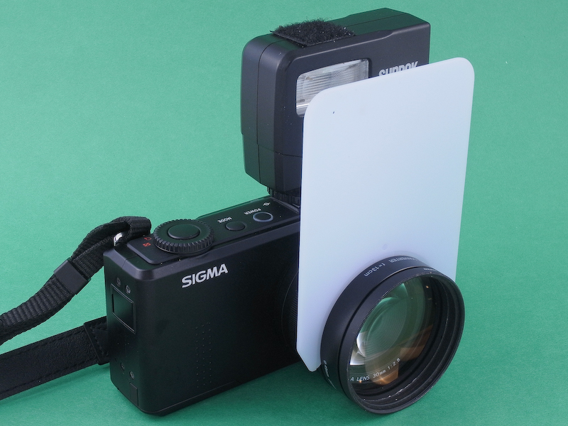 <b>DP2 Merrillに「IS/L LENS A-LIFE SIZE MACRO H.Q.CONVERTER f=13cm」、専用ディフューザー、サンパックの外付けストロボ「PX20F」を装着したところ。ディフューザーのサイズはジャストフィットで違和感がない。レンズキャップの装着も可能になり、携行性もなかなか良い。</b>