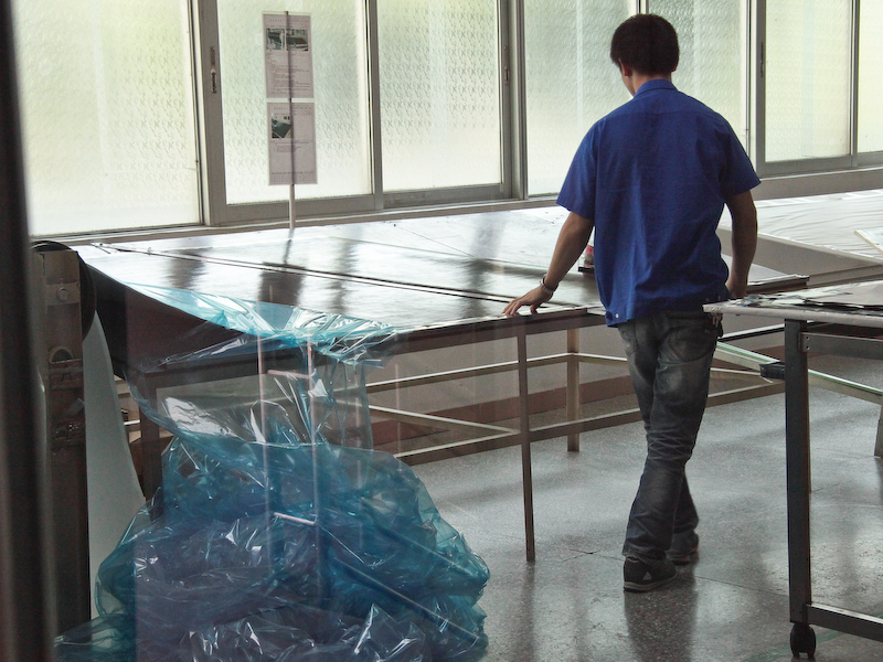 <b>カーボンシートをカットし（左）、金属の棒に巻き付けてパイプを作る（右）。焼結するまでは低温環境で作業しなければならないため、これらの作業部屋のみエアコンで室温を下げている</b>