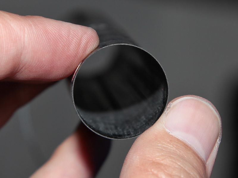 <b>左はカーボンシートを1枚巻いた状態の端面で大変薄い。一方、右のように8層重ねると数mmの厚さになり、強く押しても全く変型しなくなる</b>