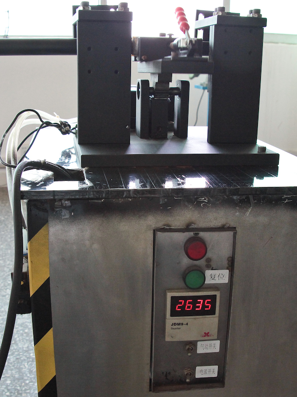 <b>ロックレバーの耐久性を検査する装置。自動でパイプを動かしてロックと解除を繰り返す。3,000回の開閉テストで問題が無いことを確認する</b>