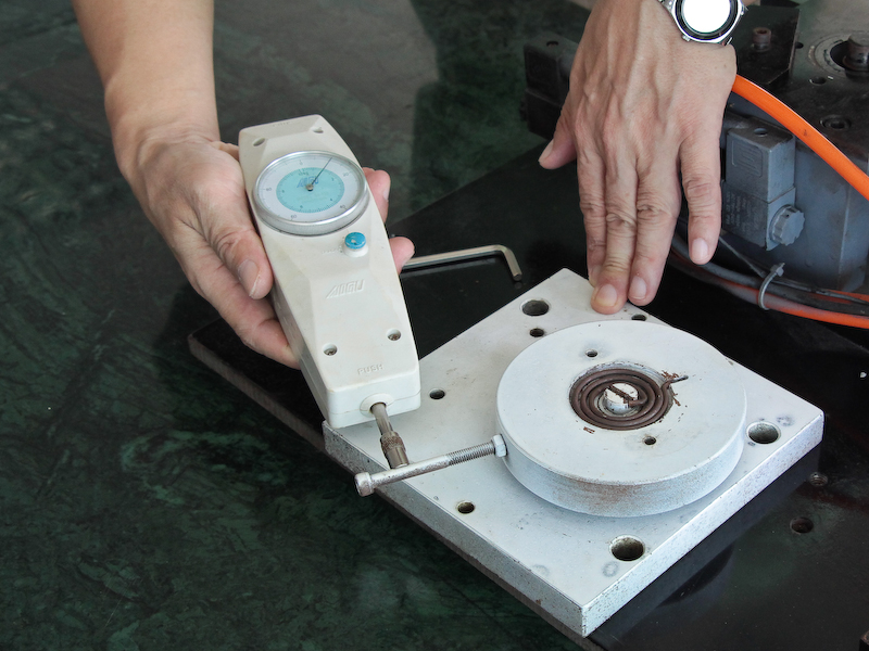 <b>同じく動画用雲台に使われるスプリング。捻りテストの後に強さが変わっていないかをテストしているところ。先のゴムタイプも同様にテストする</b>