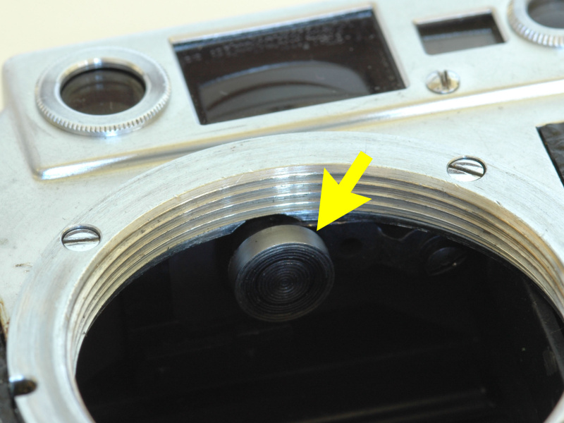 <b>バルナックライカの距離計連動コロ（矢印）。レンズ後端の前後の動きを距離計機構に伝える。</b>