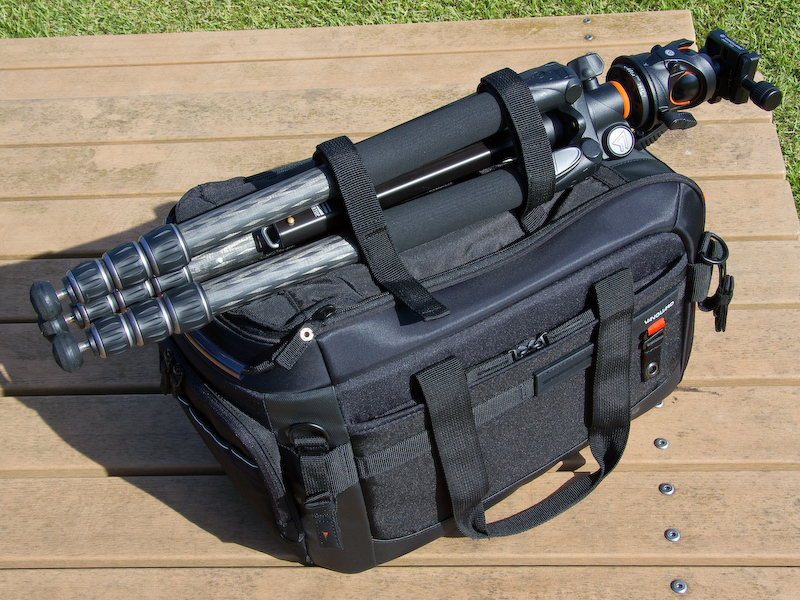 <b>バッグの上面に三脚を固定。固定用ベルトはバッグの蓋上面にあるポケットのなかに用意されている。</b>