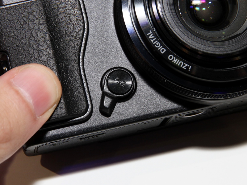 <b>レバー部分を操作するとレンズ鏡筒部のリングのクラッチが外れて無段階になる。中央はFn2ボタンになっており、割り当てた機能を利用できる</b>
