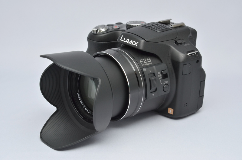 <b>バヨネット式の花型フードが付属。移動時や収納時には、こうやって逆付け収納も可能である（正方向よりもクリックストップ感が曖昧だが）。そういえば、昔持ってたDMC-FZ5に付属してた花型フードって、全長が妙に長くて攻撃的な印象を受けたけど、このフードは普通の恰好。まあ、径は少し太い気もするけど。</b>