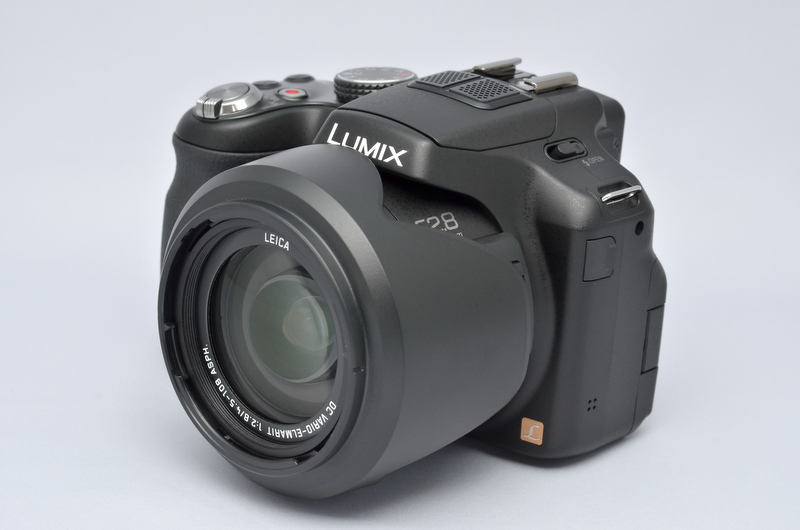 <b>バヨネット式の花型フードが付属。移動時や収納時には、こうやって逆付け収納も可能である（正方向よりもクリックストップ感が曖昧だが）。そういえば、昔持ってたDMC-FZ5に付属してた花型フードって、全長が妙に長くて攻撃的な印象を受けたけど、このフードは普通の恰好。まあ、径は少し太い気もするけど。</b>