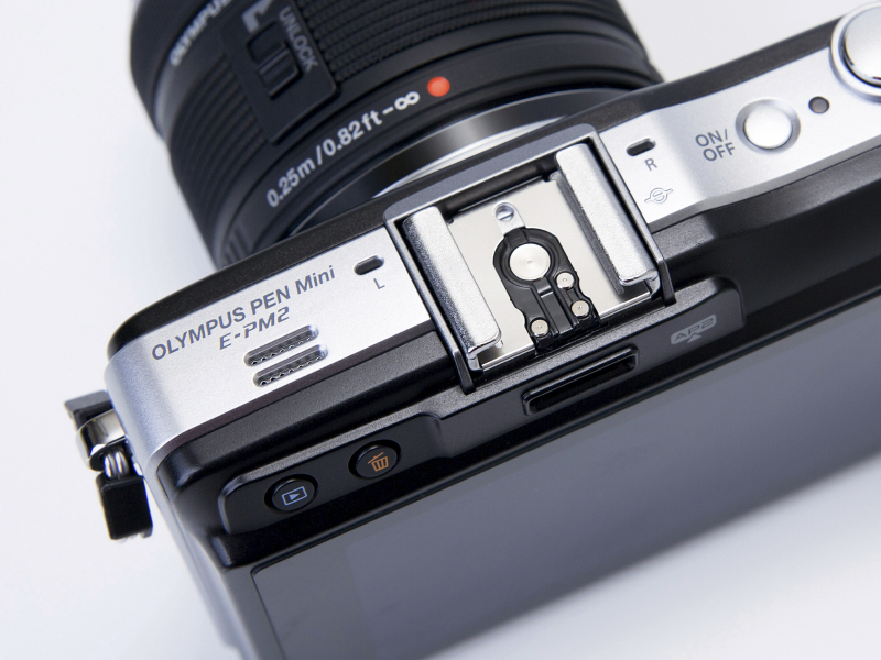 <b>カメラ上面左側。ホットシューカバーを外すとアクセサリーポートが現れる。ホットシューの両脇にはステレオマイク、左肩にはスピーカーが配置。背面液晶の左上部に再生ボタンと削除ボタンが配置された。</b>