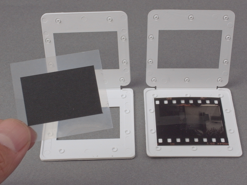 <b>まずはフレームスクリーンを製作する。35mmスライドマウントに、透明フィルムに黒ケント紙（35mmフィルムの画面より一回り小さくカット）を貼ったパーツを挟み込む</b>