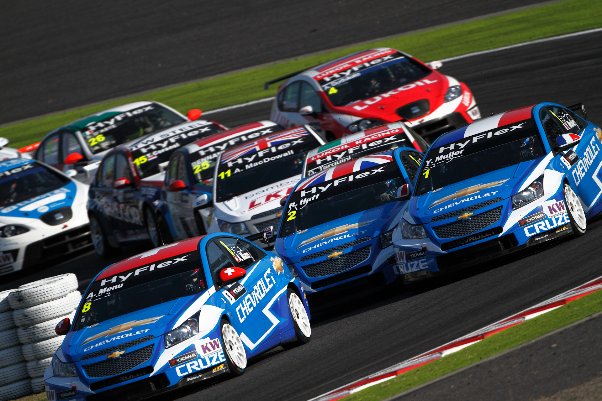 レース1のスタート直後の2コーナー立ち上がりをS字Cスタンドから撮影。スタート直後は多重クラッシュの確立も高いが、今回のレースでは比較的紳士的な?幕開けとなった。それでもこの密集感はWTCCならではで、やはりあちらこちらで前後左右ぶつかり合っていた。WTCCの象徴でもあるシボレー3兄弟(ピエール北川氏命名)をしっかり写しこみながら、そんな密集度の高さを狙った。/ キヤノンEOS 7D / EF 500mm F4 L IS USM	/ 3,000×4,500 / 1/640秒 / F4 / ISO250 / 500mm