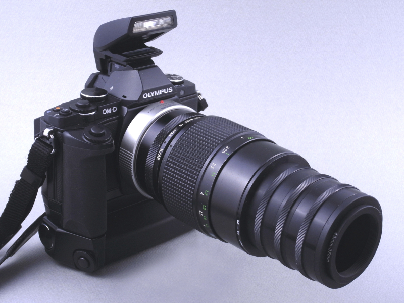 レンズにフードを装着し、さらに重量バランスをとるためE-M5本体に「パワーバッテリーホルダーHLD-6」を装着。ついでに付属ストロボ「FL-LM2」も取り付けてみた。