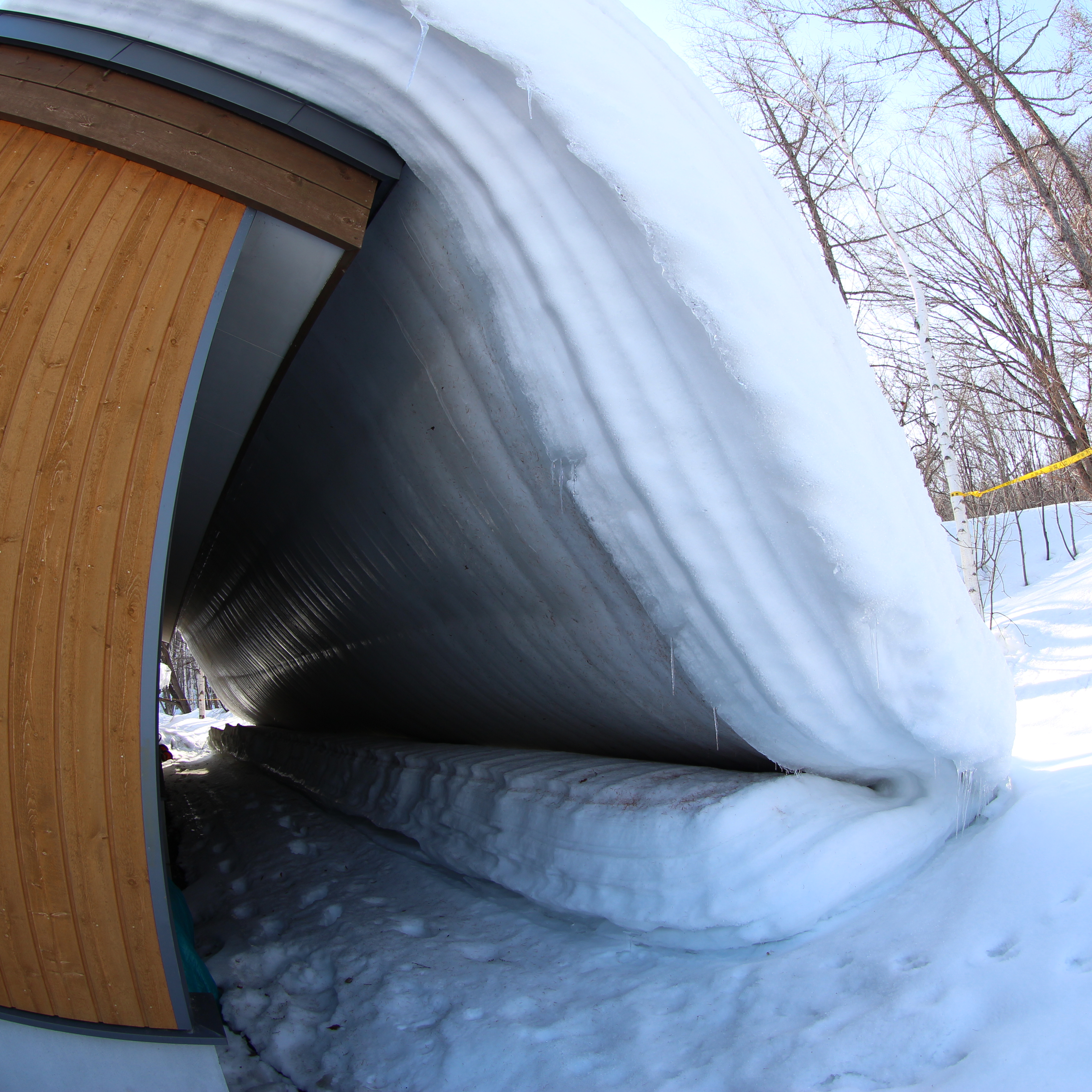 冬のあいだ閉鎖されている建物の屋根の雪がまるごと滑り落ちてきたらしい。ミルフィーユ状態。EOS M / EF 8-15mm F4 L Fisheye USM / 絞り優先AE / 3,456×3,456 / 1/160秒 / F5.6 / 0.3EV / ISO100 / WB：オート / 8mm（12.8mm相当）