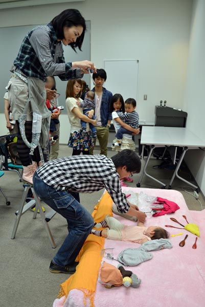 ママが脚立に乗ってカメラを構えてスタンバイ、パパは赤ちゃんにスプーンを持たせようと大奮闘！　協力して撮れた写真はきっと大切な想い出になるでしょう