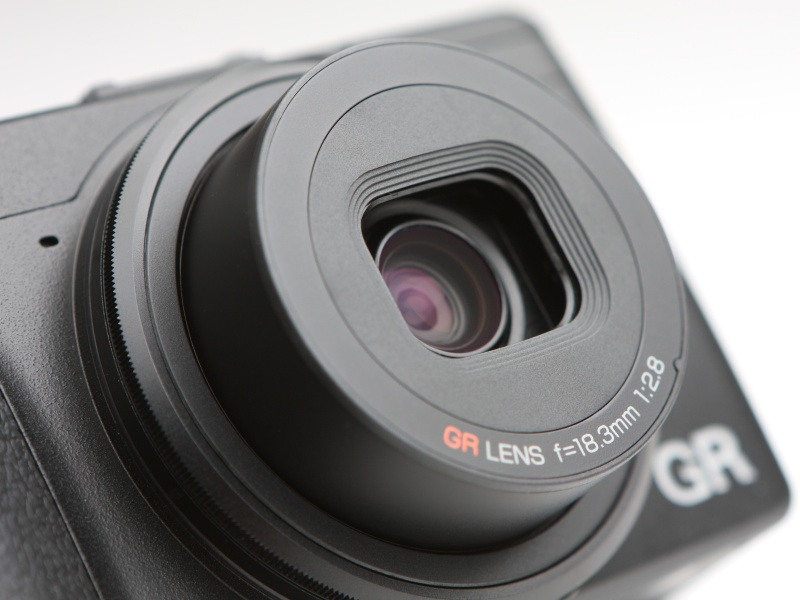 レンズはGRレンズ18.3mmF2.8を搭載。フルサイズ判換算で28mm相当の画角となる。レンズ構成は7枚5群。非球面レンズ2枚、高屈折低分散ガラス2枚を用い、画面周辺部の描写も中央部分に劣らない優れた描写特性を誇る。