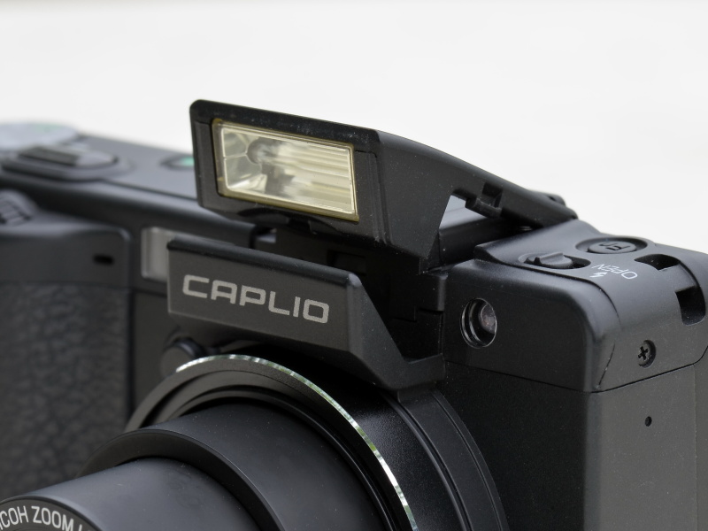 フラッシュオープンスイッチをスライドさせてポップアップさせる内蔵フラッシュ。光の到達距離（レンズ先端から）は、広角約0.2～5m、望遠約0.15～3m（ISO AUTO時）。