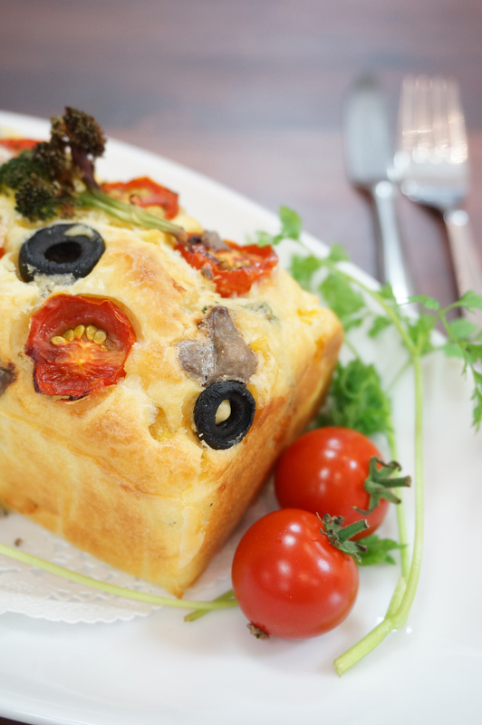 縦位置構図で撮影。ケークサレの周りに彩りのよいプチトマトとセルフィーユを添えておいしさを引き立てました。ナイフとフォークを脇役に添えることで、食卓のイメージを出ています。撮影：のぽりん さん