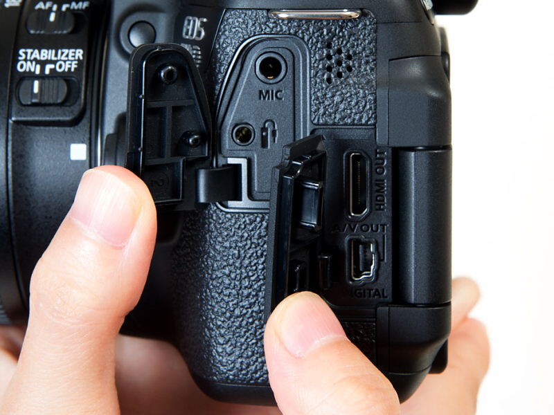 インターフェース部。リモコン端子（RS-60E3用）、外部マイク入力端子、HDMIミニ出力端子、映像/音声出力・デジタル端子がふたつの樹脂カバーで覆われている。ちなみにEOS 70Dで使用できるリモートスイッチはRS-60E3で、EOS Kissシリーズと同じもの。EOSの1桁シリーズで使用するリモートスイッチRS-80N3やタイマーリモートコントローラーTC-80N3は使用できない。