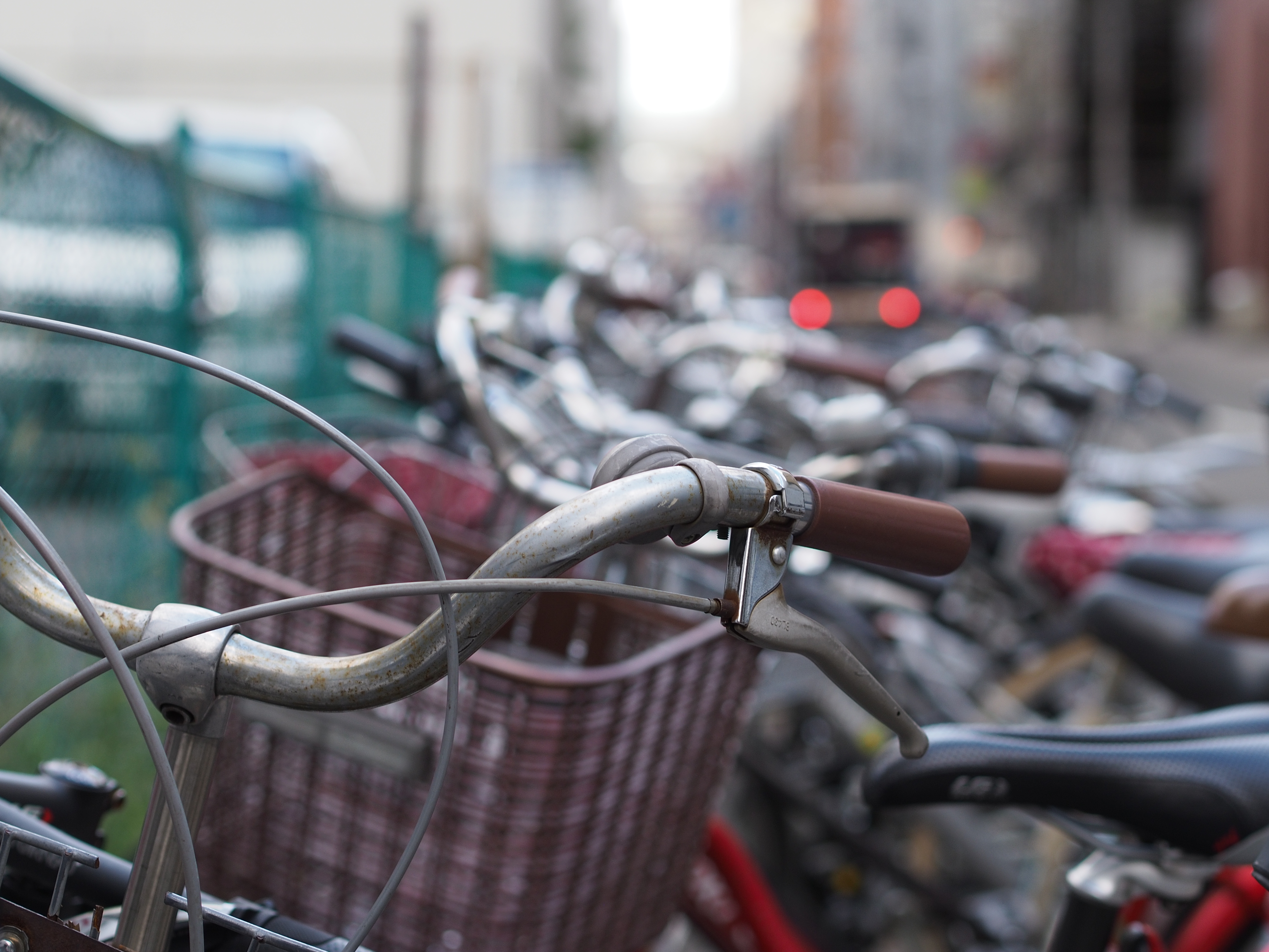 歩道にぎっしり並んでいる自転車。通りすぎる車のブレーキランプが点灯したところでシャッターを切った。M.ZUIKO DIGITAL 45mm F1.8 / 1/250秒 / F2.8 / 0EV / ISO200 / 絞り優先AE / WB：オート / 45mm