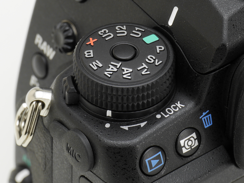 モードダイヤルは、下部のレバー操作によって回転ロック無しの状態（左）と回転ロック有りの状態（右）を切り替えられるようになった。回転ロック有り状態では、中央のボタンを押しながら回す。