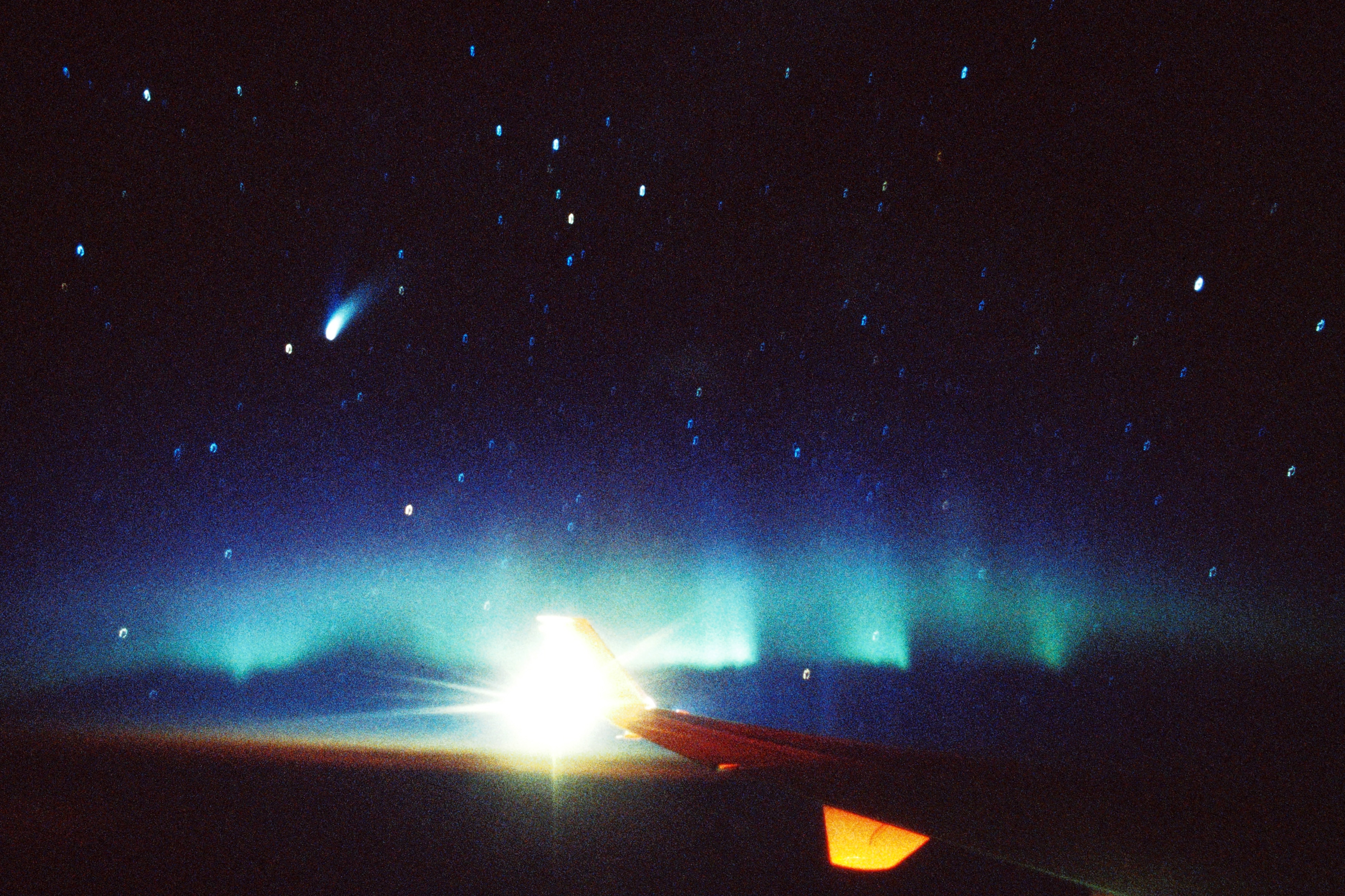 <b class="">オーロラと彗星</b><br class="">シベリア上空を飛ぶ旅客機の窓から撮影したオーロラとヘールボップ彗星です。カシオペア座も見えています。安定した飛行でしたが、わずかな揺れが星の軌跡の乱れとして写っているのが面白いところです。<br class="">35mmフィルム（ISO400）で撮影 / 24mm F2レンズ使用