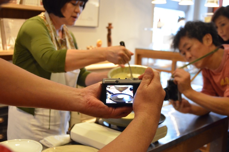 大川先生の調理風景を撮影する福岡先生と福原先生。調理をする人の邪魔にならない程度に声をかけてコミュニケーションをとり、パンケーキの流し込みやひっくり返すタイミングを撮影していました。
