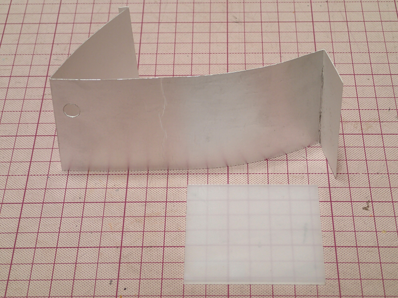 内蔵する反射板は、ケント紙の裏面にアルミホイルをスプレーのりで貼付け、反射効率を上げている。手前は透過光スクリーンのパーツで、乳白色アクリル板（2mm厚）をカッターで切り出した。