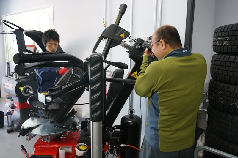 タイヤチェンジャーでの作業を撮影する礒村さん